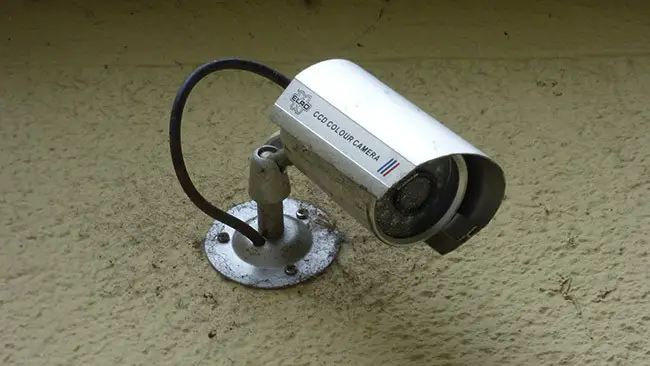 A grey security camera installed on an external wall
