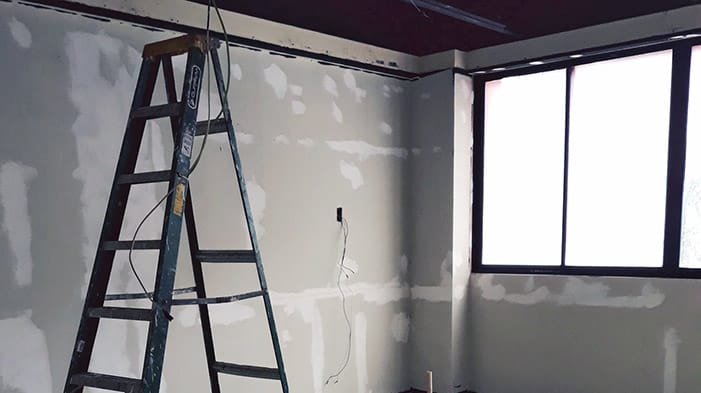 A ladder next to a wall in a room that is being renovated 