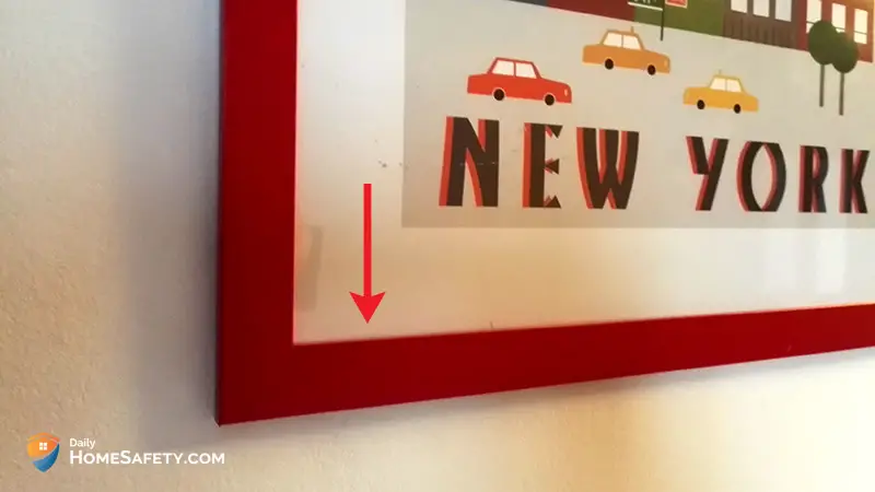 A close-up of a picture with red frame and red arrow showing a possible hiding spot under the frame