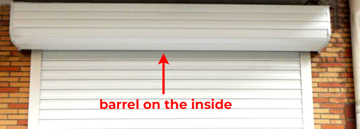 White roll-up garage door barrel with red arrow showing barrel on the inside