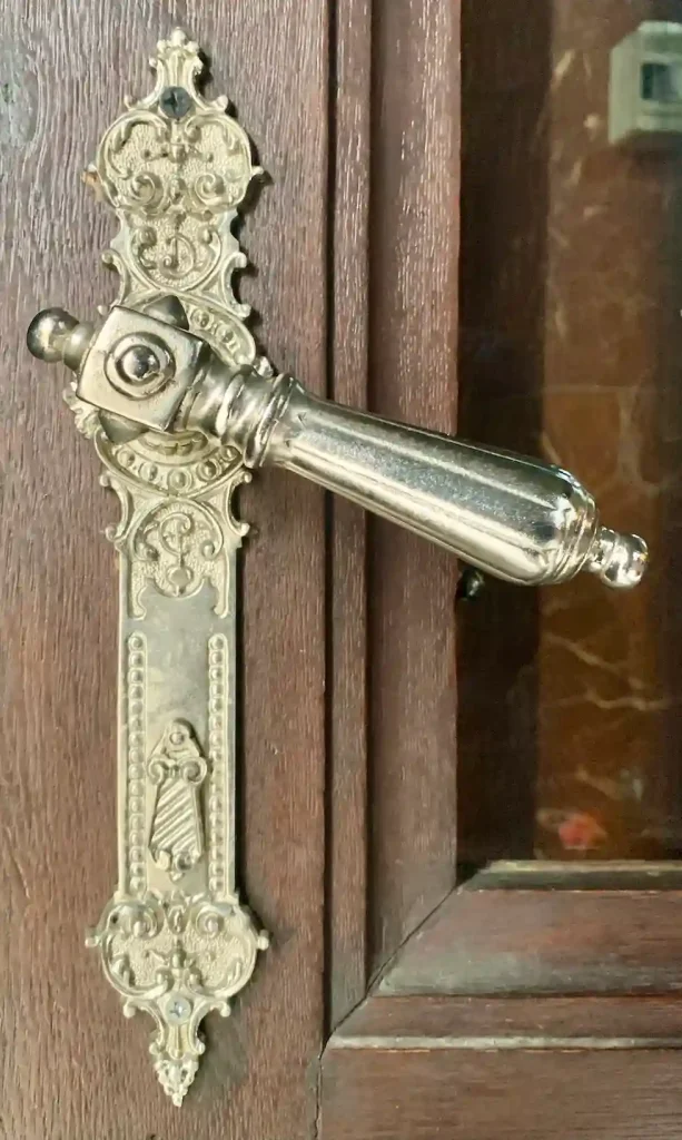 A gold antique handle on a wooden door